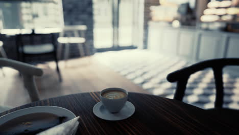 close-up of a latte art coffee cup on a wooden table in a cafe.