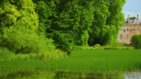 big-mansion-house-residency-by-the-lake-overgrown-with-grass-and-flora-beautiful-vibrant-colours-looking-like-from-a-modern-fairy-tale-mysterious-place-nobody-around-cinematic-atmosphere