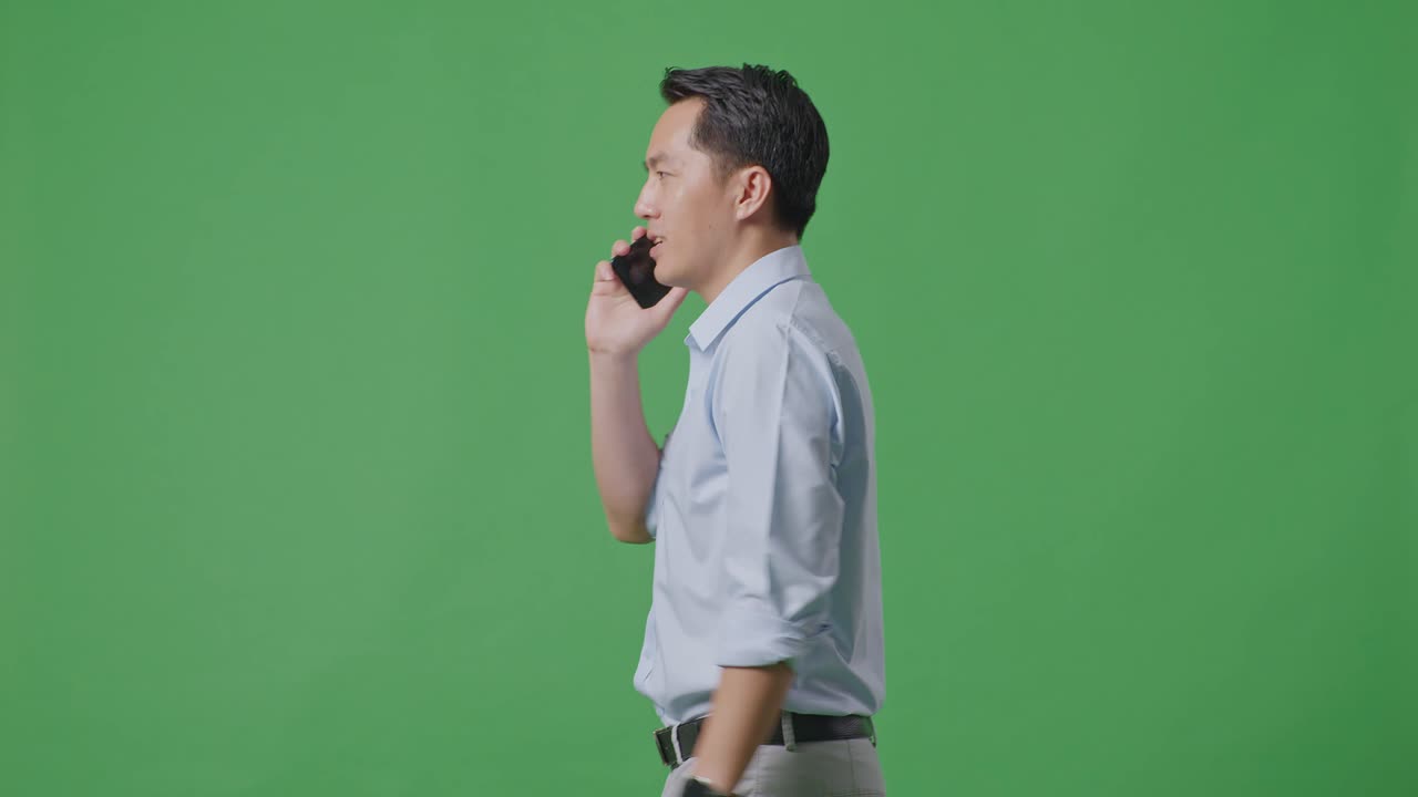 스튜디오에서 녹색 화면 배경에서 는 동안 휴대 전화로 이야기하는 아시아 사업가의 측면 시각