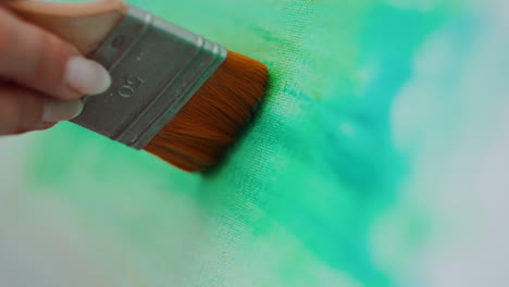 Woman painting on canvas with green colors
