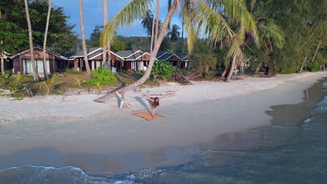 girl doing yoga pose standing on beach under palm trees