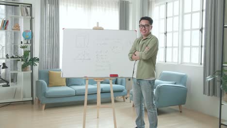 asian male teacher with glasses crossing arms and smiling to camera while teaching math at home
