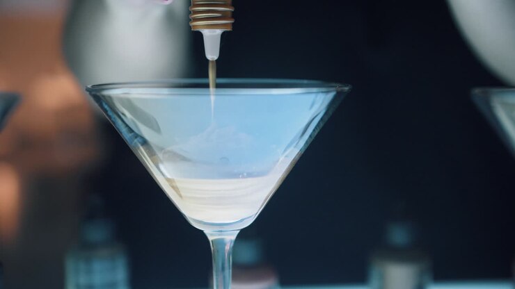 Colorista di un salone di parrucchieri che mescola la tintura in un elegante bicchiere da martini con il cliente che osserva