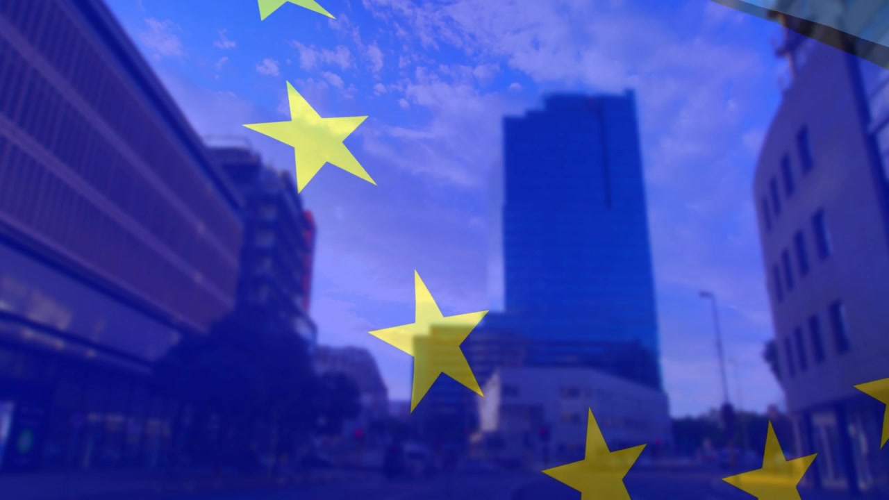 Vento impetuoso, bandiera UE traslucida che sventola su una strada urbana, rivelando una torre di vetro