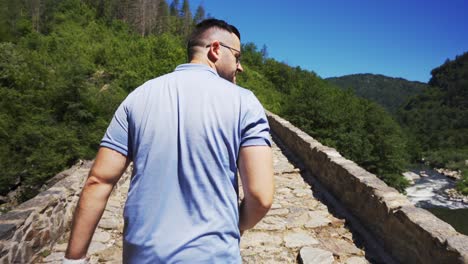 turista paseando mientras cruza el puente del diablo ubicado cerca de las montañas rodope, en ardino, bulgaria