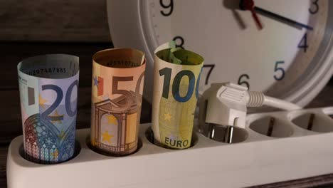 closeup shot of money and a socket with a clock behind them.