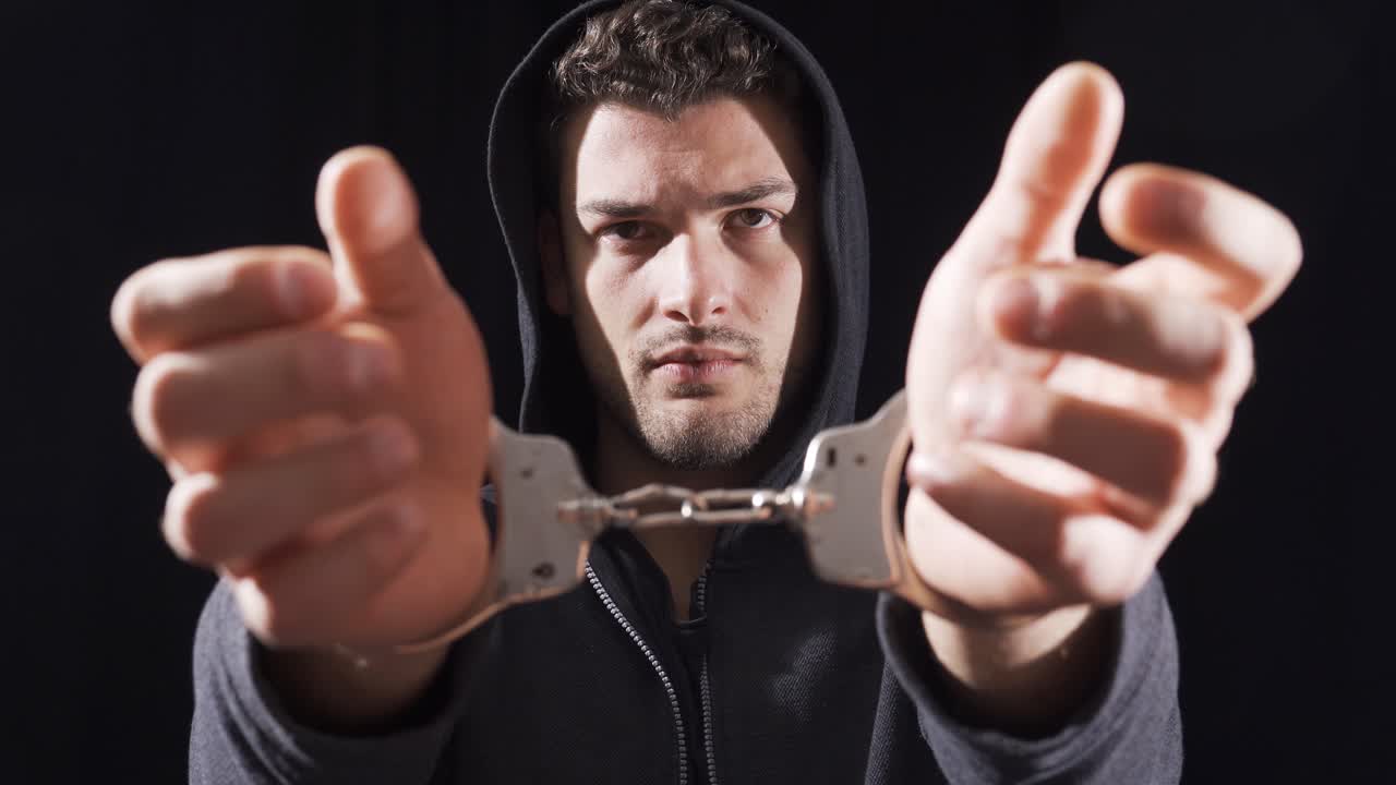 hombre esposado mirando a la cámara y molesto.