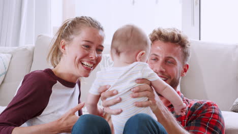 Young-couple-sitting-on-floor-at-home-with-baby,-close-up