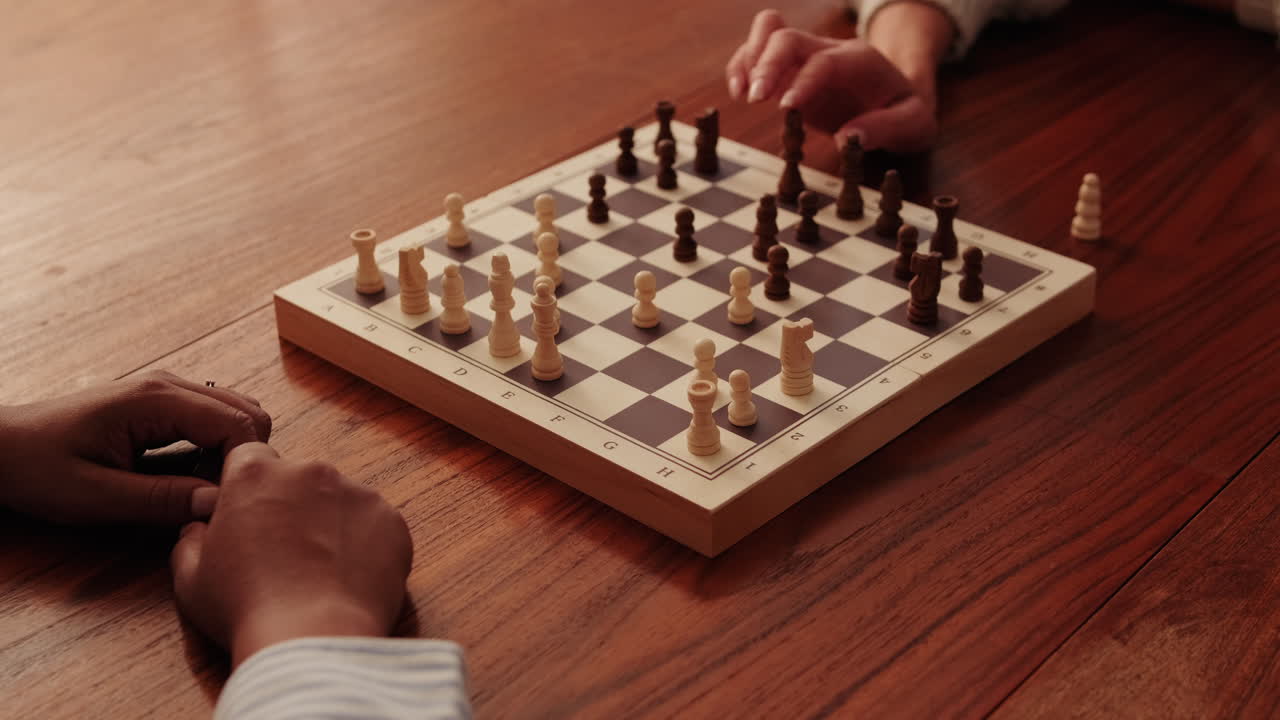Two People Playing Chess on a Wooden Board
