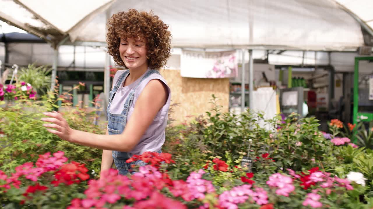 Giardiniere sorridente che si prende cura dei fiori in serra
