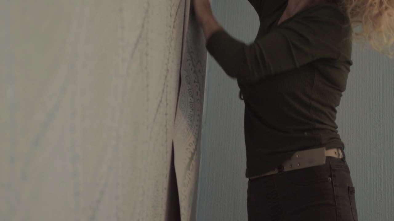 실내 집 방에 벽지를 걸고 있는 여성 데코레이터