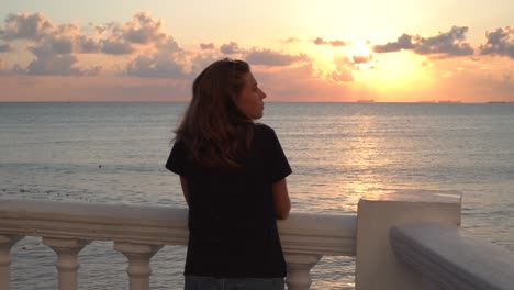 mujer viendo la puesta de sol en un balcón