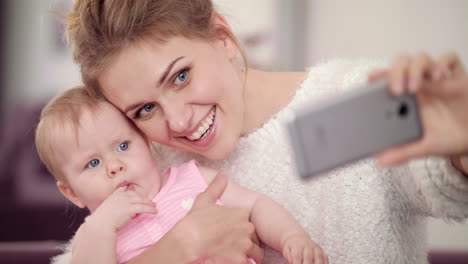 Madre-Sonriente-Haciendo-Una-Foto-Selfie-Con-Una-Niña.-Mujer-Con-Foto-Movil-Niño