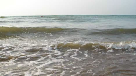small waves comes in on a sandy beach with a blue sky