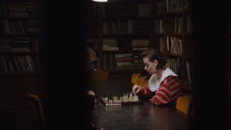 pareja jugando al ajedrez en una biblioteca