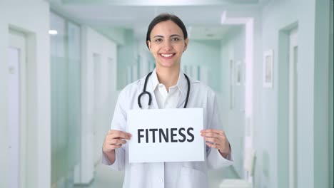 Happy-Indian-female-doctor-holding-FITNESS-banner