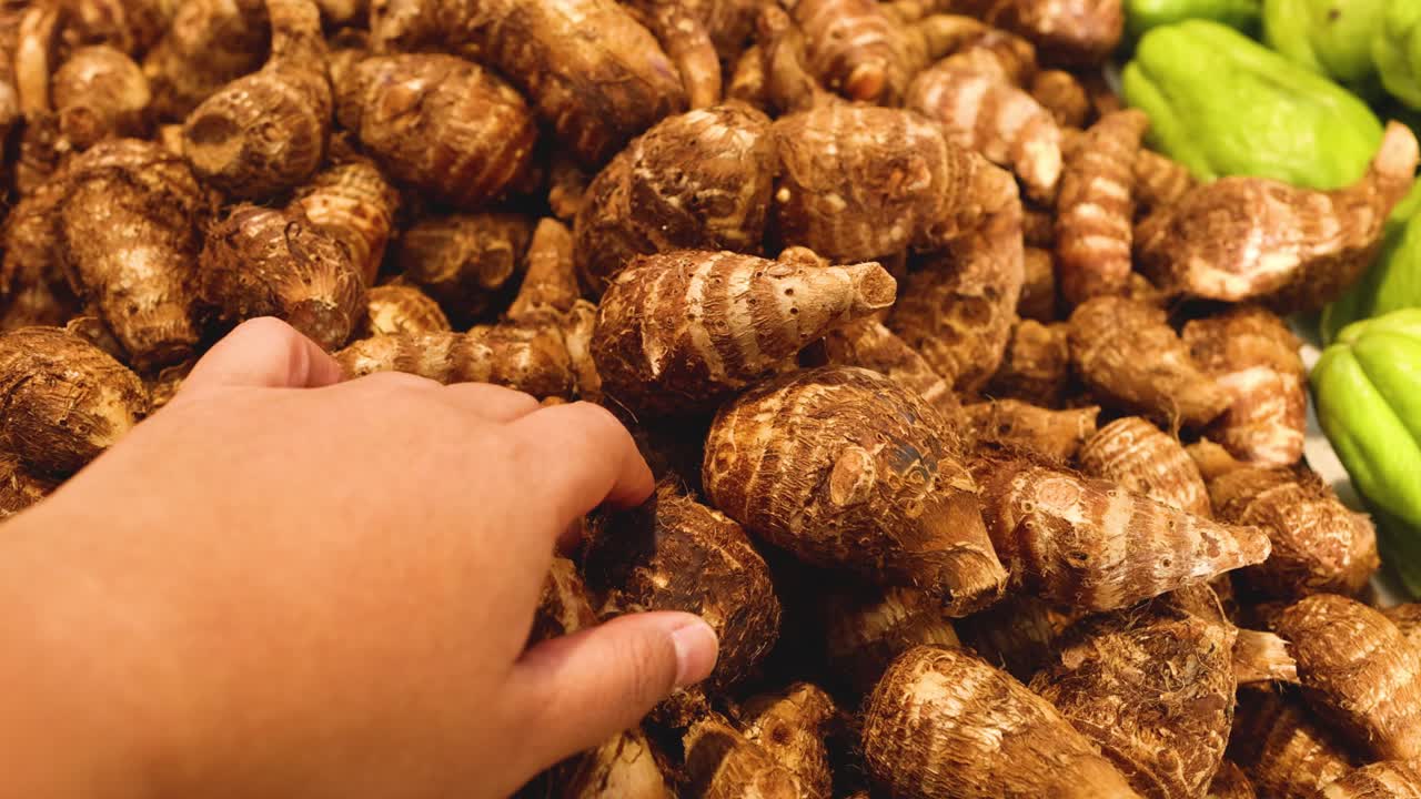 Hand picking taro from a market display