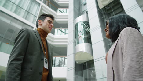 multiethnic colleagues shaking hands and talking in office center