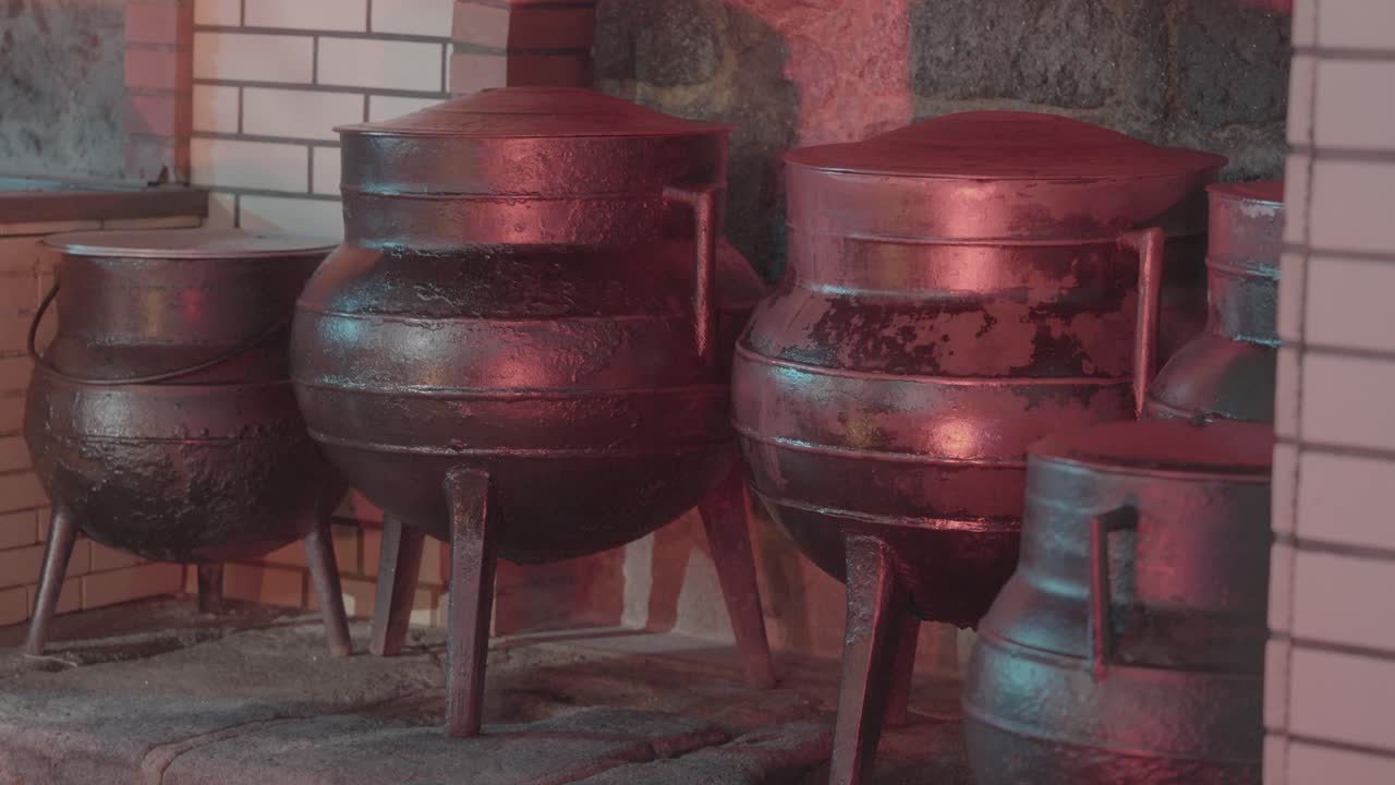 Large metal pots standing on heated indoor cooking hearth