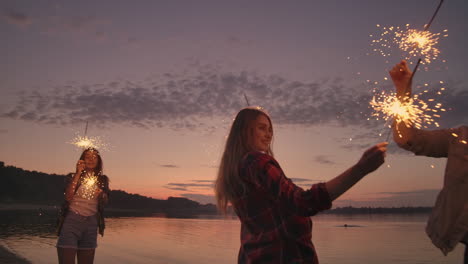 A-group-of-friends-of-men-and-women-merry-celebrate-the-holiday-on-the-beach-with-sparklers-and-fireworks.-Slow-motion-night-party-beach-party.