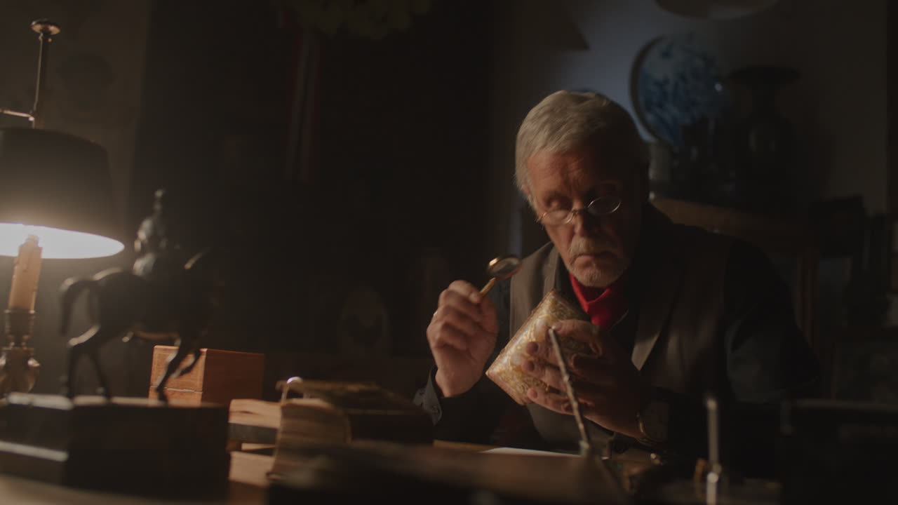 Older passionate antique dealer write note in his office at night