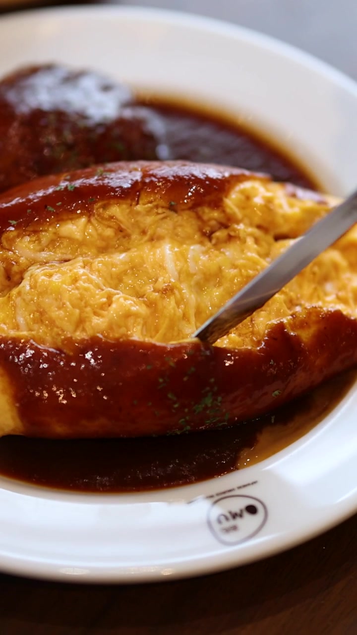 En kniv skjærer gjennom en luftig omelett, som avslører kremete egg over rik demi-glace-saus