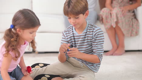 hermanos jugando a un juego de mesa en el suelo