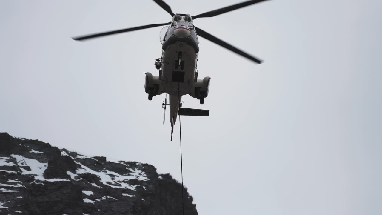 승강 케이블과 부하가 부착된 화물 헬리 ⁇ 터가 도달하기 어려운 산악 지형에 착륙합니다.