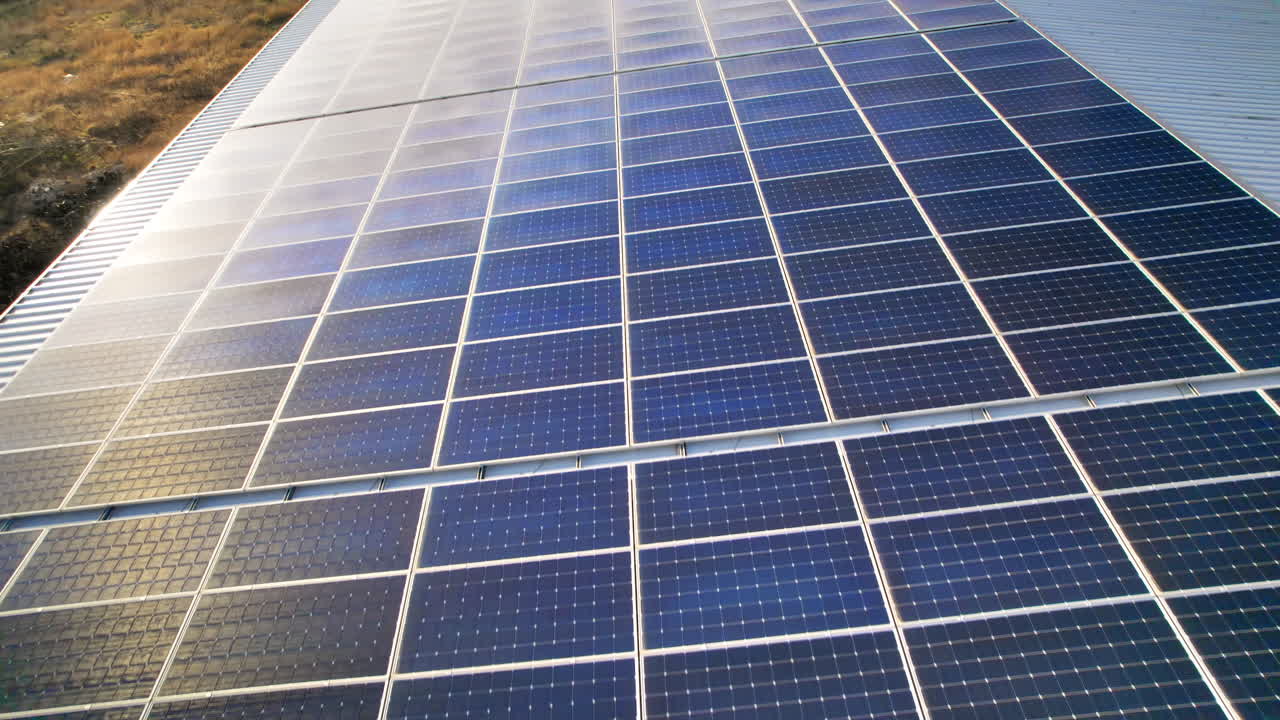 Visão aérea de drone de vários painéis solares no telhado de um prédio de fábrica. Temática de ecologia