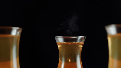 hot steaming tea in traditional glasses on a dark background