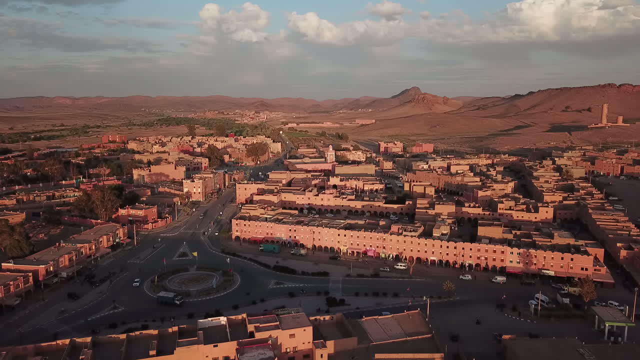 Riprese aeree cinematiche in 4K di una città nel deserto all'ora d'oro. Calda luce del tramonto che illumina edifici tradizionali color terra con uno sfondo montuoso. Perfetto per contenuti di viaggio, cultura e architettura.