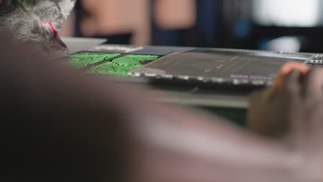 bartender's hand cleaning surface behind bar counter, green heineken neon sign glowing. blurred shot focuses on bartender s arm while working, creating intimate, close-up view of bar area