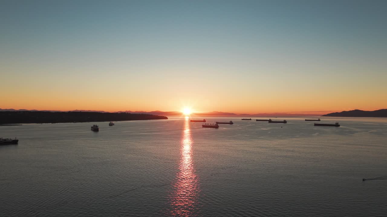 Wide tilting up aerial shot of Burrard Inlet at sunset during a clear evening in Vancouver, British Columbia, Canada. 4K