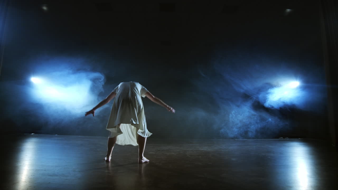 mujer en vestido blanco en el escenario con humo bailando ballet moderno