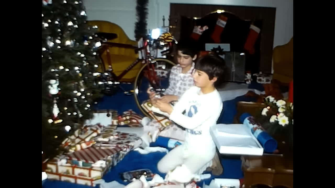 Man and Boy Sitting in Front of Christmas Tree. CIRCA USA - 1970s: A man and a boy from the 1970s in the USA sit together in front of a decorated Christmas tree.