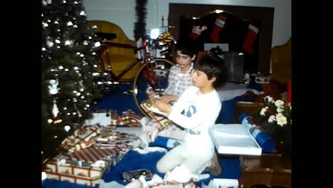 man and boy sitting in front of christmas tree. circa usa - 1970s: a man and a boy from the 1970s in the usa sit together in front of a decorated christmas tree.