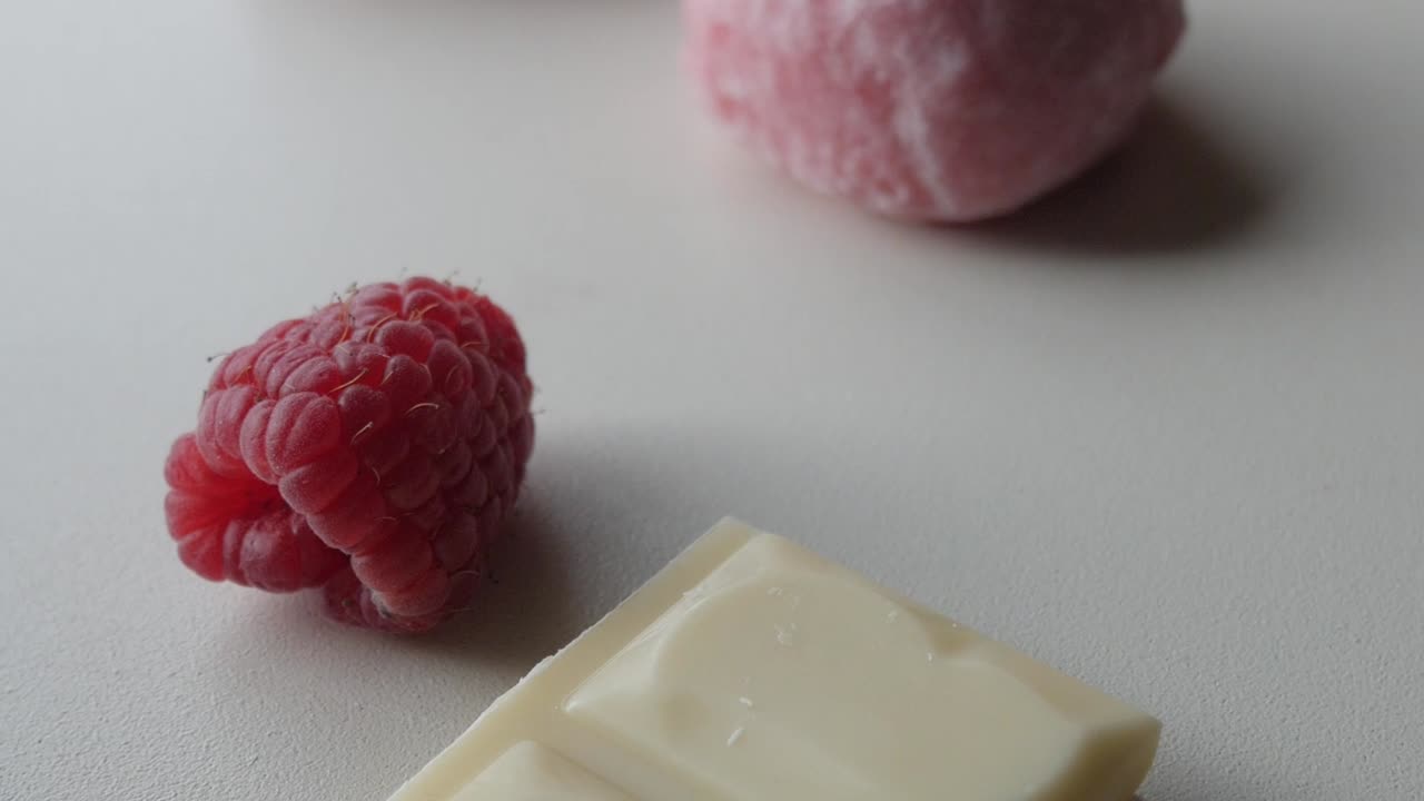 Fresh raspberries and white chocolate on a light surface for a sweet dessert concept