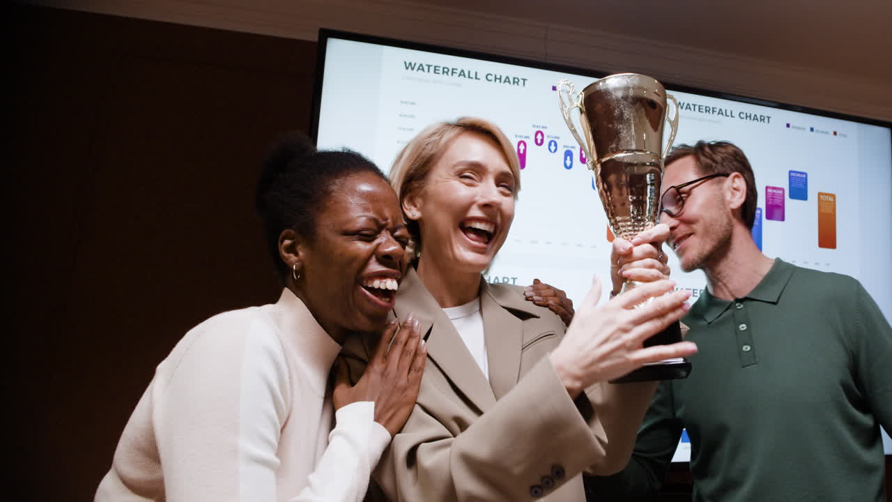 Business Team Joyfully Celebrates Success with a Trophy in the Office