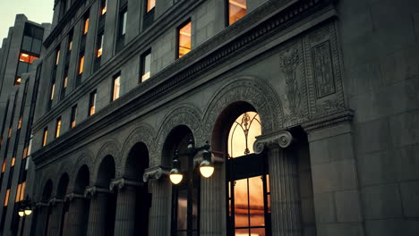 a stately building with ornate details and windows glowing at dusk.