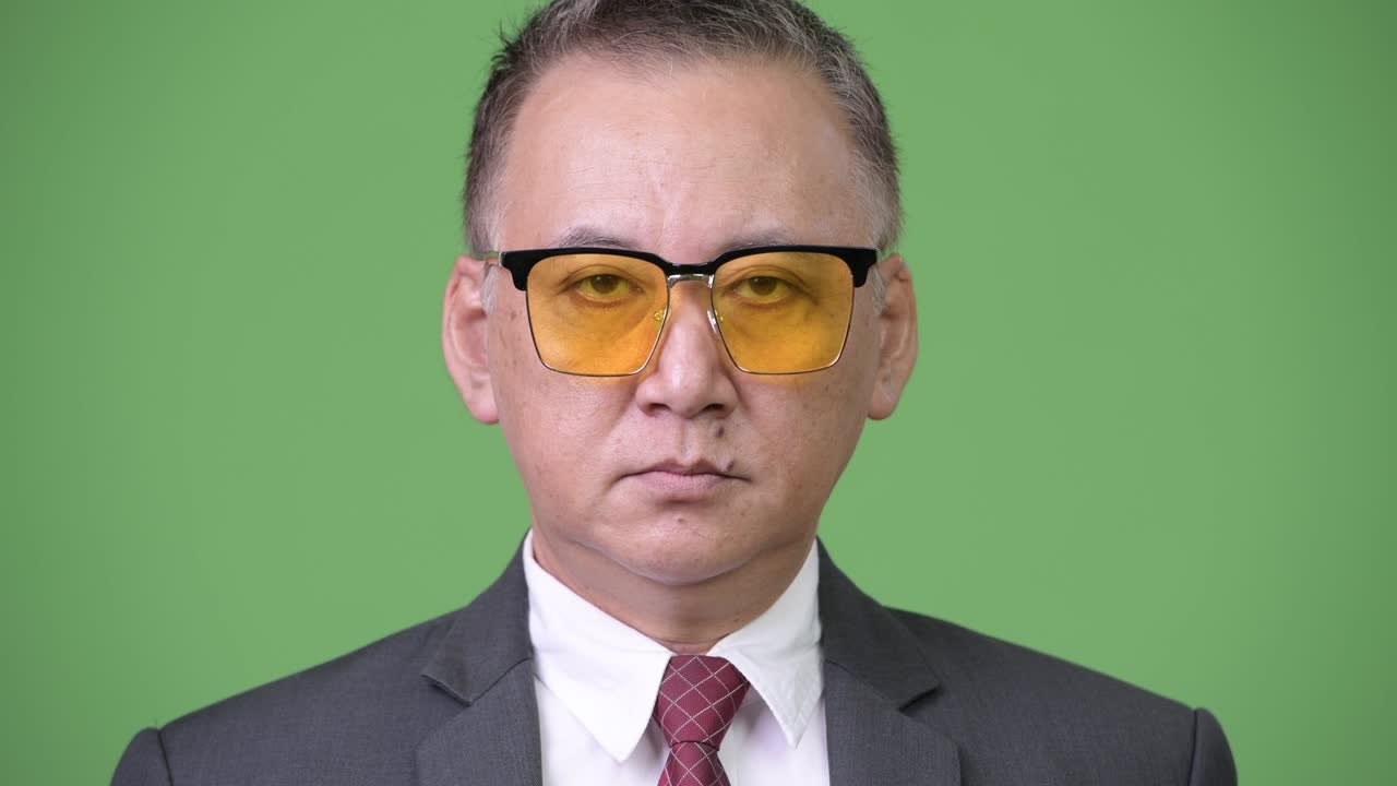 초록색 바탕에 선글라스를 입은 성숙한 일본인 사업가