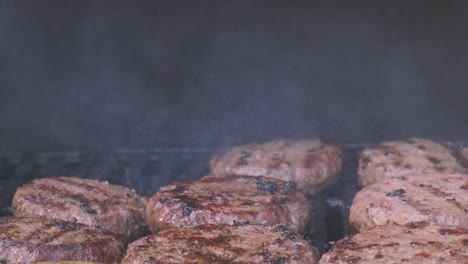 slow motion of chef flipping beef burger with flames rising after hot oil and juices from meat falls onto hot charcoals. high protein summer outdoor food. delicious social eating.
