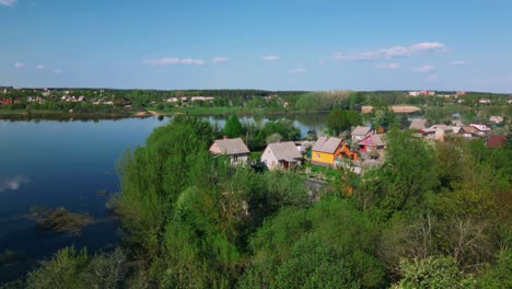 drone crane down with view on village next to blue river ending with blossom spring rural landscape