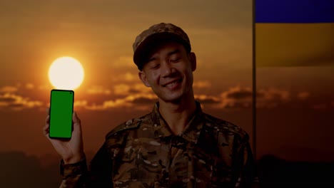 soldado con teléfono inteligente al atardecer