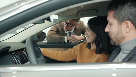 couple test driving a car in a showroom