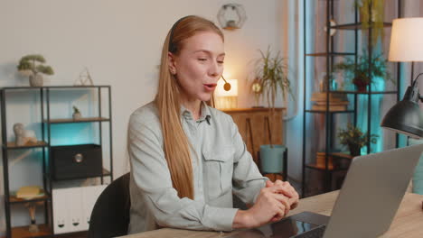 mature female customer service representative with headset using laptop computer at home office desk