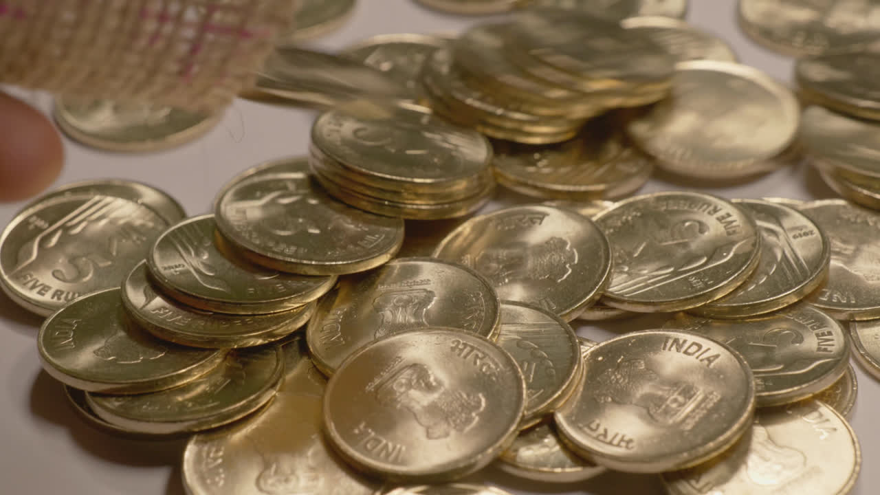 slow motion of pouring indian 5 rupees gold coated coins through a small Jute Gunny bag in a table, 4k, stable shot