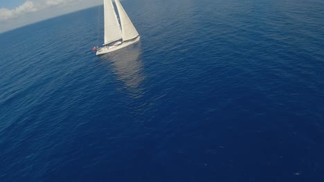 drone fly towards the white yacht floating in the blue sea in the daytime