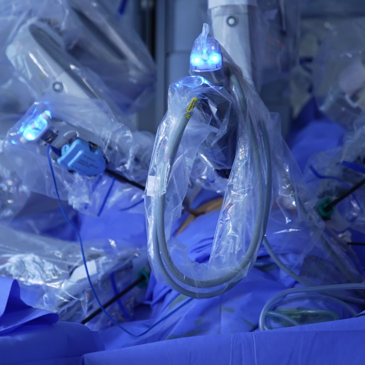 Numerous arms of robotic surgery equipment covered in plastic. Technological modern apparatus performing minimal invasion surgery
