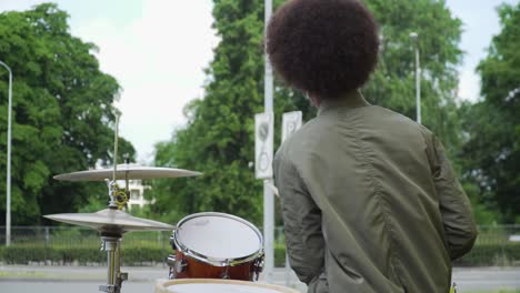 young afro teen playing loud drums outside