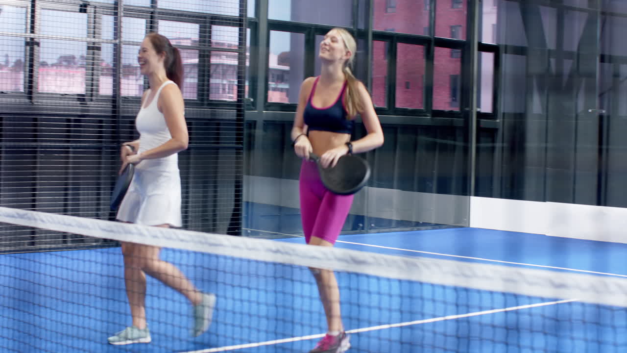 Group of friends enjoying padel tennis match, celebrating on indoor court with smiles